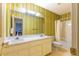 Full bathroom with double sinks, a large mirror, shower-tub combo and unique striped wall design at 350 W Lake Trl, Mebane, NC 27302