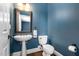 This modern powder room offers a toilet and sink with a wooden mirror and decorative lighting at 3905 Grandbridge Dr, Apex, NC 27539