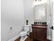 Powder room with dark vanity, dark hardwood floors, and vintage bronze fixtures at 3905 Grandbridge Dr, Apex, NC 27539
