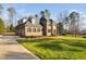Sprawling brick and stone home with a lush front lawn, a long driveway, and an attached three-car garage at 3905 Grandbridge Dr, Apex, NC 27539