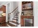 Elegant hallway features a staircase, dark wood flooring, and a custom bar area with wine storage and a mini-fridge at 3905 Grandbridge Dr, Apex, NC 27539