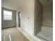 Bright bathroom featuring tiled walk-in shower with bench and stone pebble flooring at 4889 Grosbeak Ct, Mebane, NC 27302
