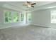 Large bedroom features tray ceilings, a ceiling fan, and large windows overlooking the yard at 4889 Grosbeak Ct, Mebane, NC 27302