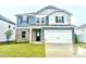 Charming two-story home featuring blue siding, brick, a black front door, and an attached two-car garage at 768 Riguard Way, Wendell, NC 27591