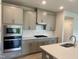 Modern kitchen with stainless steel appliances, gas cooktop, and stylish gray cabinetry at 768 Riguard Way, Wendell, NC 27591