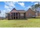 Rear exterior view of a brick home featuring a screened porch, stone accents, and a well-maintained lawn at 7936 Nc 42, Holly Springs, NC 27540