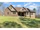 Stunning stone and brick home with a manicured lawn and architectural roofline detail at 7936 Nc 42, Holly Springs, NC 27540