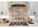 Close up of the gas cooktop with a decorative tile backsplash and granite countertops at 7936 Nc 42, Holly Springs, NC 27540