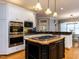 Well-equipped kitchen with stainless steel appliances, center island cooktop, and white cabinets at 101 Hedwig Ct, Cary, NC 27518