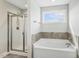 Bright bathroom features a shower, separate tub, and natural light from a window at 105 Hanover Ct, Clayton, NC 27527