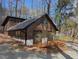 Exterior view of the home displaying its wooden siding, black roof, and surrounding natural landscape at 1269 Manns Chapel Rd, Pittsboro, NC 27312