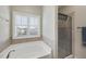 Bright bathroom featuring a tub with shuttered window and glass shower at 1319 Rodessa Run, Raleigh, NC 27607