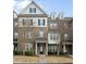 Charming brick townhome featuring black shutters, a covered entry, and manicured landscaping at 1319 Rodessa Run, Raleigh, NC 27607