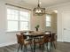A dining room with an elegant light fixture, a wooden table, and large windows that let in lots of natural light at 177 Magenta Rose Dr, Raleigh, NC 27610