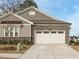 Close up view of the garage featuring stone accents and a paved driveway leading to a charming single-Gathering home at 177 Magenta Rose Dr, Raleigh, NC 27610