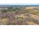 Aerial view showcasing a luxurious modern farmhouse nestled in a serene, wooded landscape at 2418 Crossroads Ave, Hillsborough, NC 27278