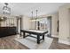 Well-lit game room with a black pool table, hardwood floors, and large windows for natural light at 2418 Crossroads Ave, Hillsborough, NC 27278