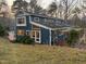 View of the back of the house, featuring many windows, a brick patio, and lush greenery at 2819 Meacham Rd, Chapel Hill, NC 27516