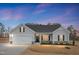 Charming single-story home boasts a two-car garage, neutral siding, and covered entry at twilight at 295 Barbour Farm Ln, Four Oaks, NC 27524