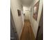 Hallway view with hardwood flooring, neutral walls, and several pieces of wall art at 300 Grove St, Oxford, NC 27565