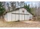 A metal barn building with a decorative sign on the front, sitting on bare ground with trees in the background at 3320 Tree Farm Rd, Hillsborough, NC 27278