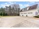 Three car garage with doors, attached to a light yellow house with blue sky and green trees in the background at 3320 Tree Farm Rd, Hillsborough, NC 27278