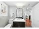 Neutral bathroom featuring white vanity, modern fixtures, mirror and toilet with window at 400 Edinburgh Dr, Cary, NC 27511
