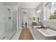 Bright bathroom features a glass shower, soaking tub, and grey vanity with lots of natural light at 49 Bonterra Way, Chapel Hill, NC 27516