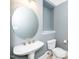 Half-bath offers a pedestal sink, round mirror and toilet, and is painted a calming gray-blue color at 501 Finsbury St # 100, Durham, NC 27703
