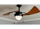 Close up of a contemporary ceiling fan featuring wood grain blades and a glowing light fixture at 501 Liberty Rose Dr, Morrisville, NC 27560