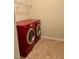 Laundry room features tiled floor and modern, red front-load washer and dryer at 501 Liberty Rose Dr, Morrisville, NC 27560