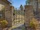 Ornate wrought iron garden gate framed by brick pillars, leading to the property at 601 Golfers Vw, Pittsboro, NC 27312