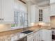 Well-lit kitchen sink with granite countertops, custom cabinetry, and a view of the backyard at 601 Golfers Vw, Pittsboro, NC 27312