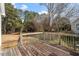 Back deck with wooden flooring and railing overlooking greenery in a lush backyard at 7201 Spanglers Spring Way, Raleigh, NC 27610