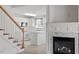 View of the kitchen from the stairs featuring white cabinets and a marble fireplace at 7201 Spanglers Spring Way, Raleigh, NC 27610