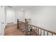 A well-lit hallway featuring wood floors, white trim, and dark railing at 9004 Penny Rd, Raleigh, NC 27606