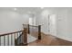 Bright hallway featuring hardwood floors, white walls, and a dark wood stair railing at 9004 Penny Rd, Raleigh, NC 27606