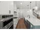 A chef's kitchen with stainless steel appliances, white cabinetry and hardwood flooring at 9004 Penny Rd, Raleigh, NC 27606