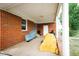 Covered back porch of a brick home with outdoor storage and access to the backyard at 10166 Buffalo Rd, Clayton, NC 27527
