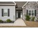 Close-up view of home's front entrance featuring stone and vinyl siding and manicured landscaping at 203 Mitchell Manor Dr, Angier, NC 27501