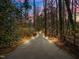 Long gravel driveway with landscape lighting guides you home through a serene wooded property at 3217 Stoneyford Ct, Raleigh, NC 27603