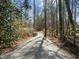 Gravel driveway leading to a beautiful home surrounded by lush greenery and mature trees at 3217 Stoneyford Ct, Raleigh, NC 27603