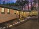 Brick home featuring a covered porch with wood railing and walkway at dusk at 3217 Stoneyford Ct, Raleigh, NC 27603