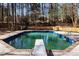 A diving board sits next to this sparkling in-ground pool surrounded by a private wooded backyard at 3217 Stoneyford Ct, Raleigh, NC 27603