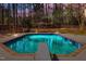 A diving board sits next to this sparkling in-ground pool surrounded by a private wooded backyard at 3217 Stoneyford Ct, Raleigh, NC 27603