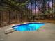 Backyard pool at night with diving board and concrete deck amid lush trees at 3217 Stoneyford Ct, Raleigh, NC 27603