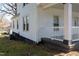 White vinyl-sided home with dark skirting, multiple windows, and a cozy covered front porch at 347 W Trade St, Burlington, NC 27217