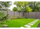 Landscaped backyard with artificial turf, stepping stones, and a modern fence at 4300 Camelot Dr, Raleigh, NC 27609