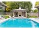 Beautiful backyard pool with a covered outdoor fireplace, lounge chairs, and lush greenery at 4300 Camelot Dr, Raleigh, NC 27609