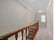 Neutral carpeted hallway featuring wooden banister and a large window at the end of the hall at 502 Forest Court, Carrboro, NC 27510